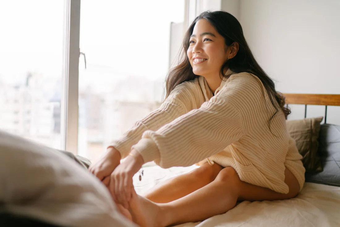 ベッドの上でストレッチをする女性